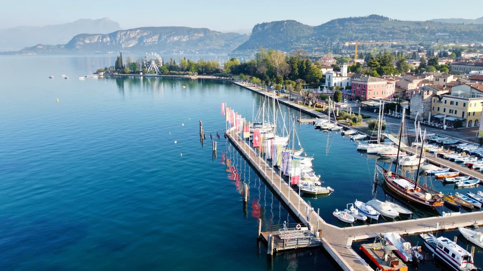 Marina mit Segelbooten an einer Gardasee-Stadt, Bergpanorama im Hintergrund
