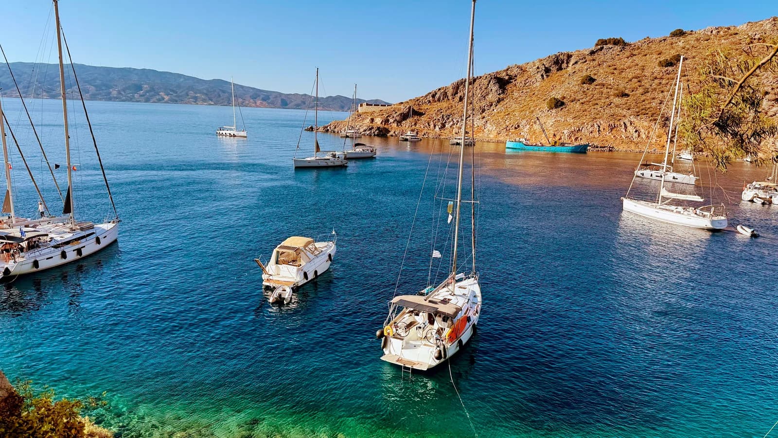 Segelyachten ankern in einer geschützten Bucht vor karger griechischer Küste