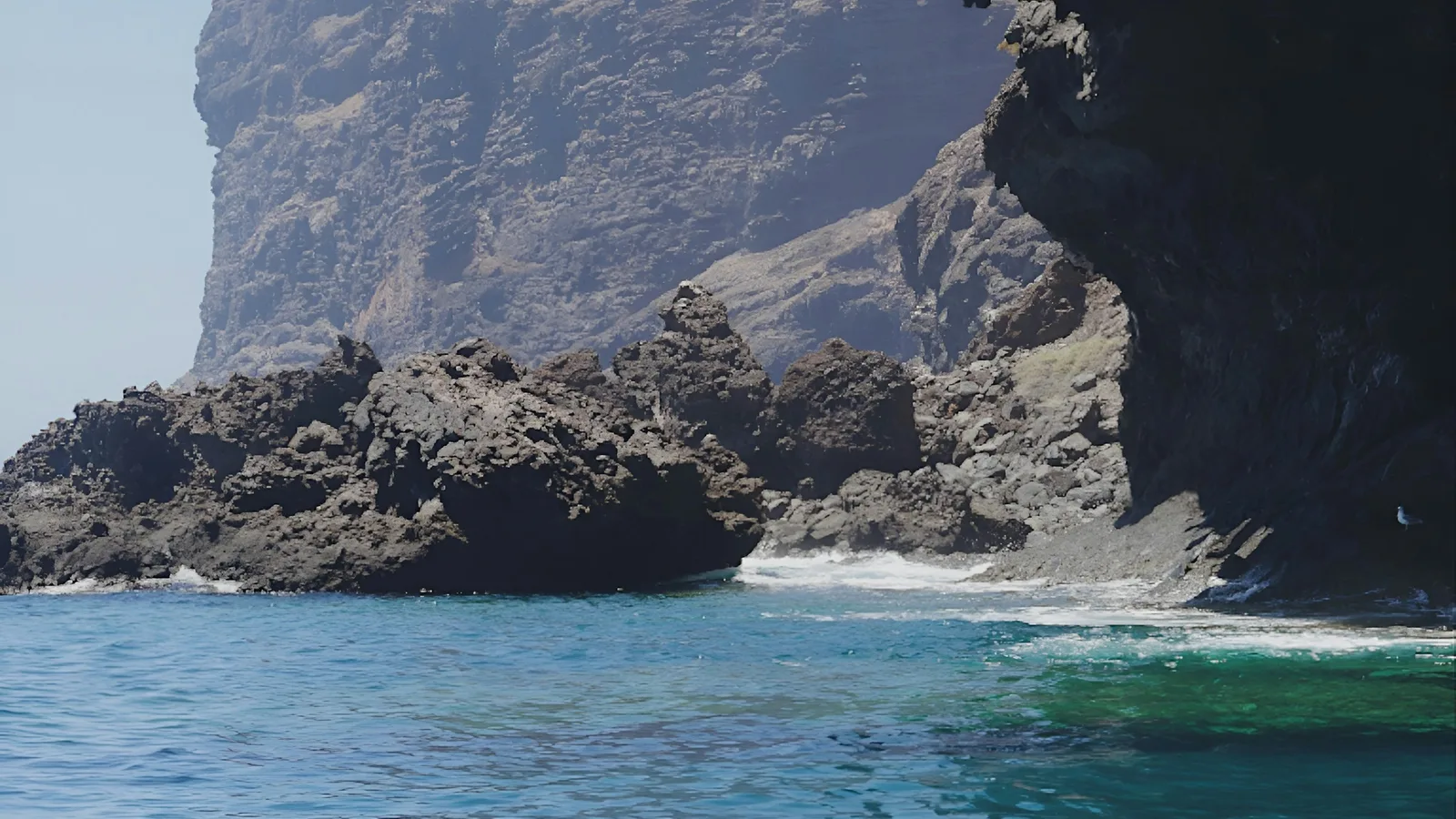 Sonnenbeschienene Vulkanklippen über türkisem Wasser auf Teneriffa